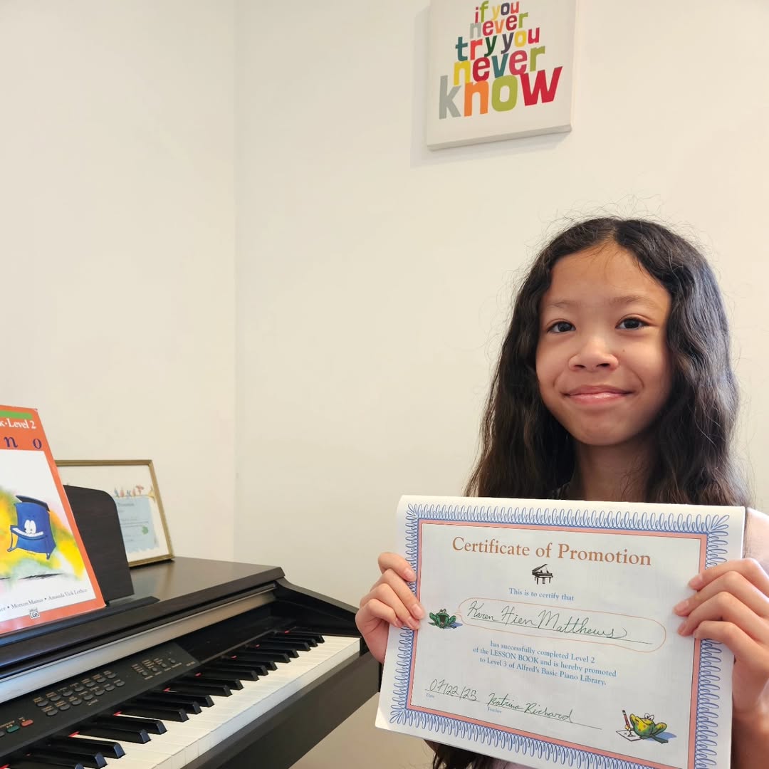 A student with her certificate beside the piano